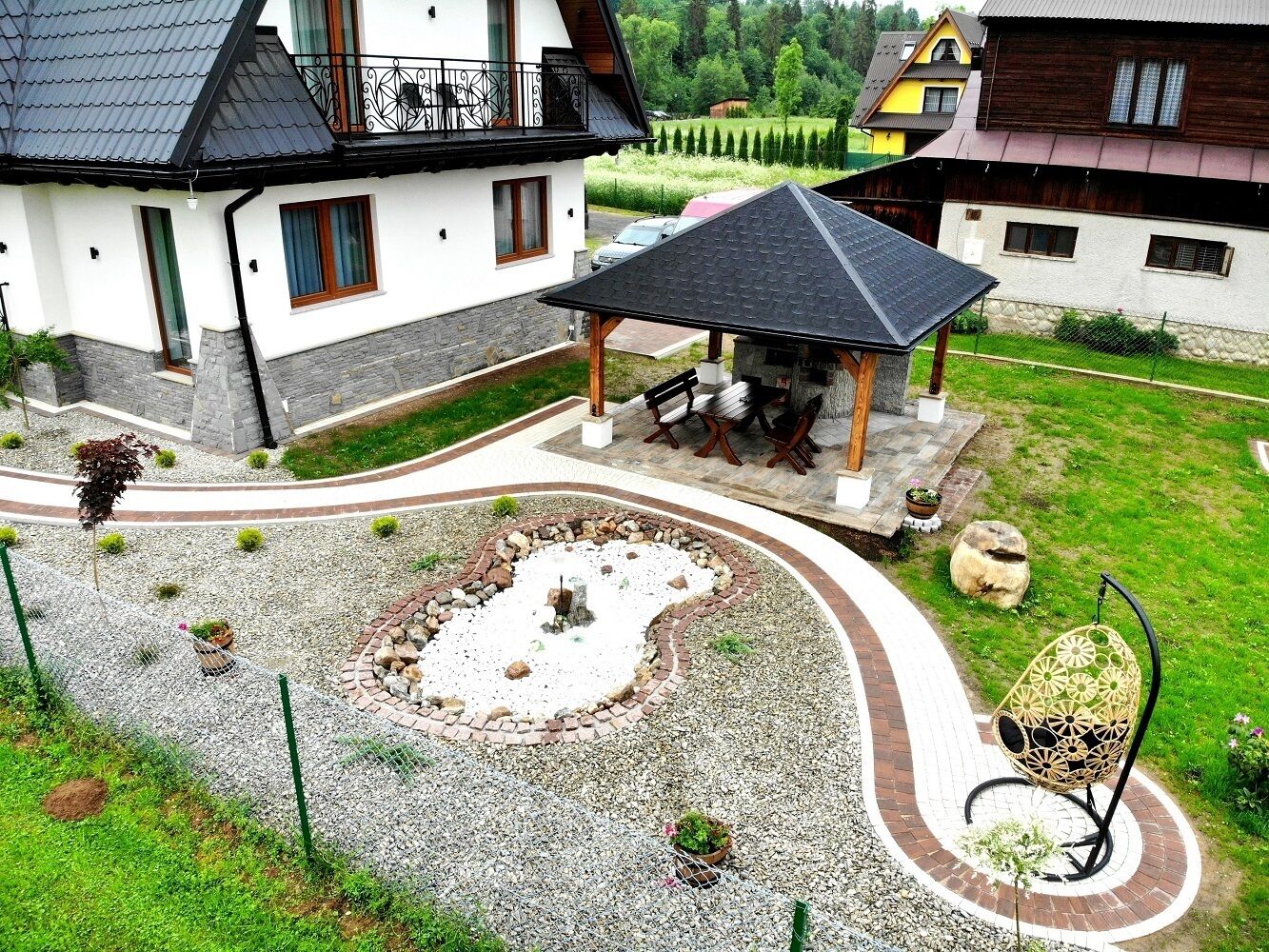 A house with a garden, a gazebo, and a decorative chair.