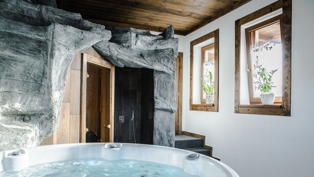 A spa area with a hot tub, wooden door, and a window with a plant.