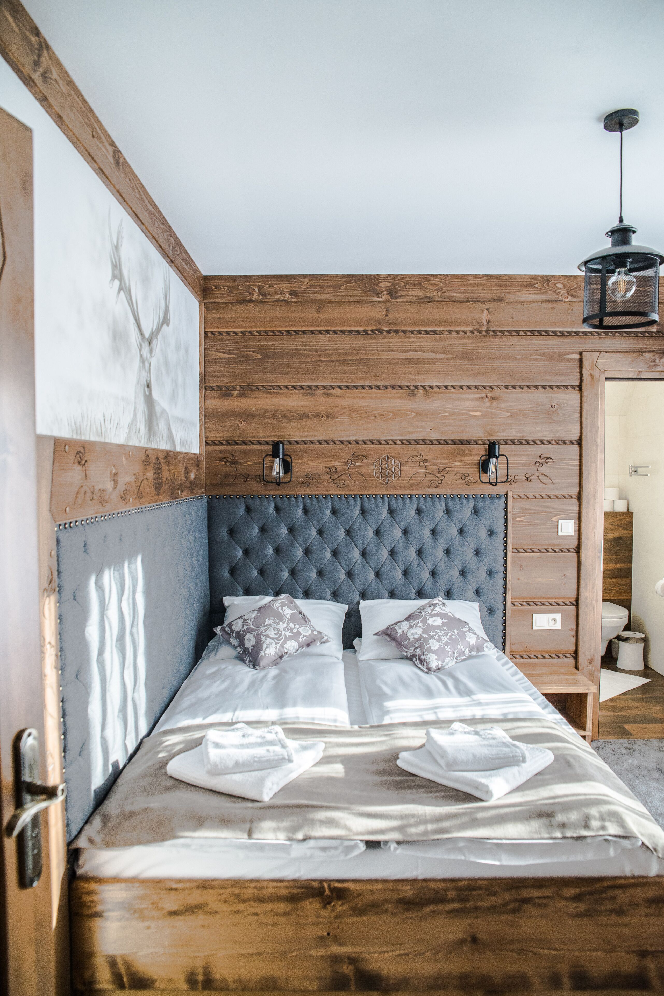 Ein Bett mit einem geblatteten Kopfteil, zwei Kissen und einer Decke.