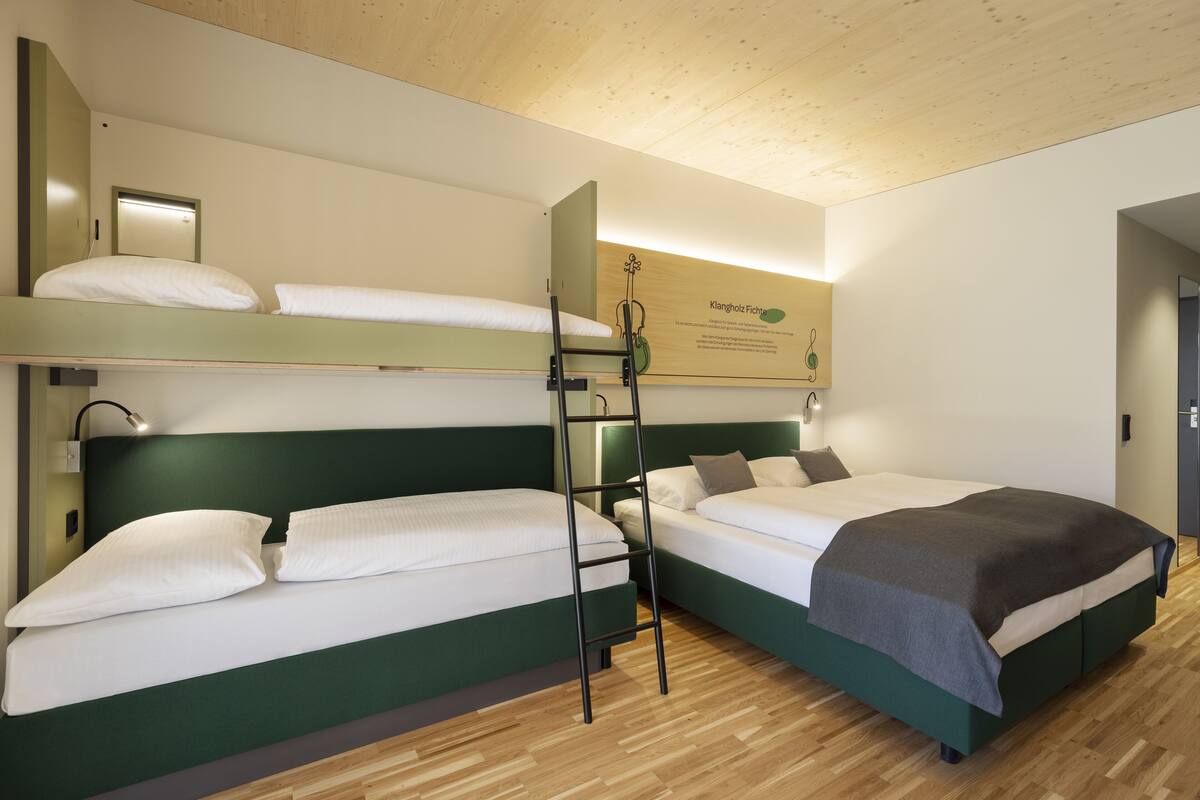 Een hotelkamer met twee bedden, een ladder en een wandlamp.