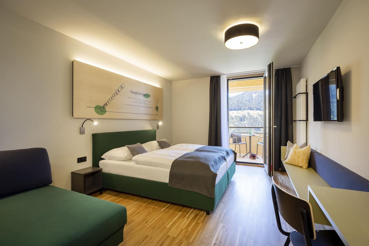 Een moderne hotelkamer met een bed, een bureau en uitzicht op de omgeving.