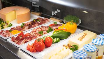A buffet with various cheeses, meats, vegetables, and condiments.