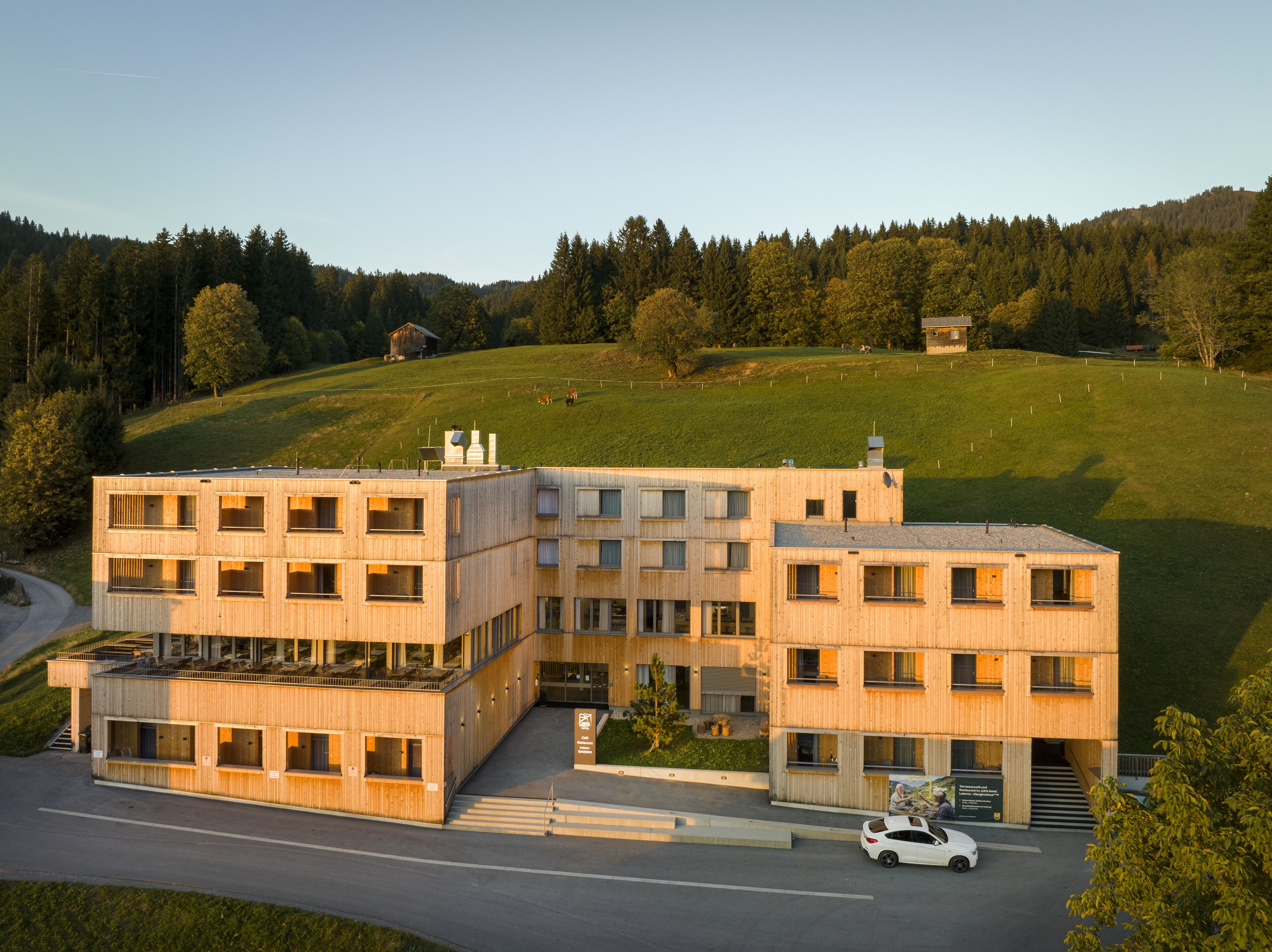 Un immeuble moderne à plusieurs étages, doté d’un toit plat, de grandes fenêtres et d’un espace de stationnement.