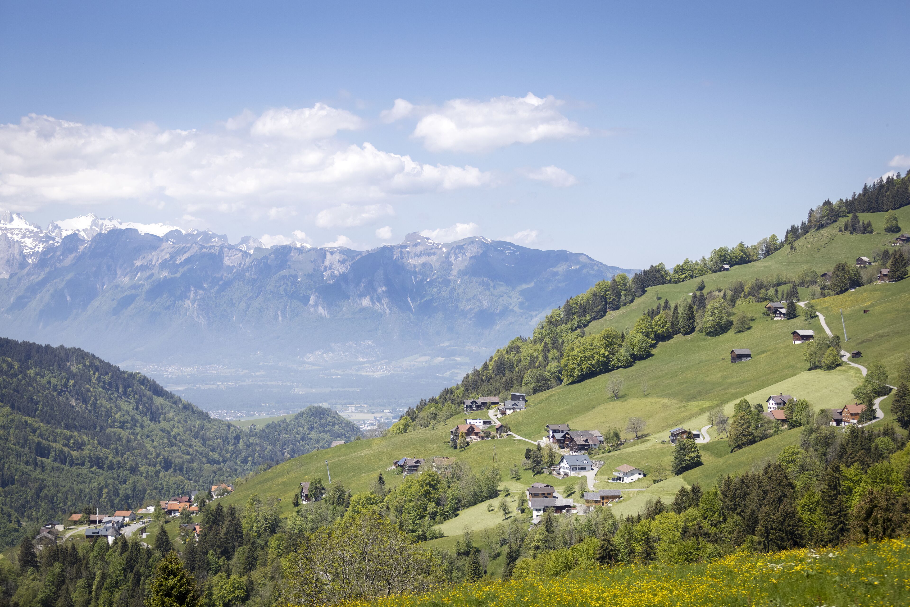 Eine gebirgige Landschaft mit verstreuten Häusern und blauem Himmel.