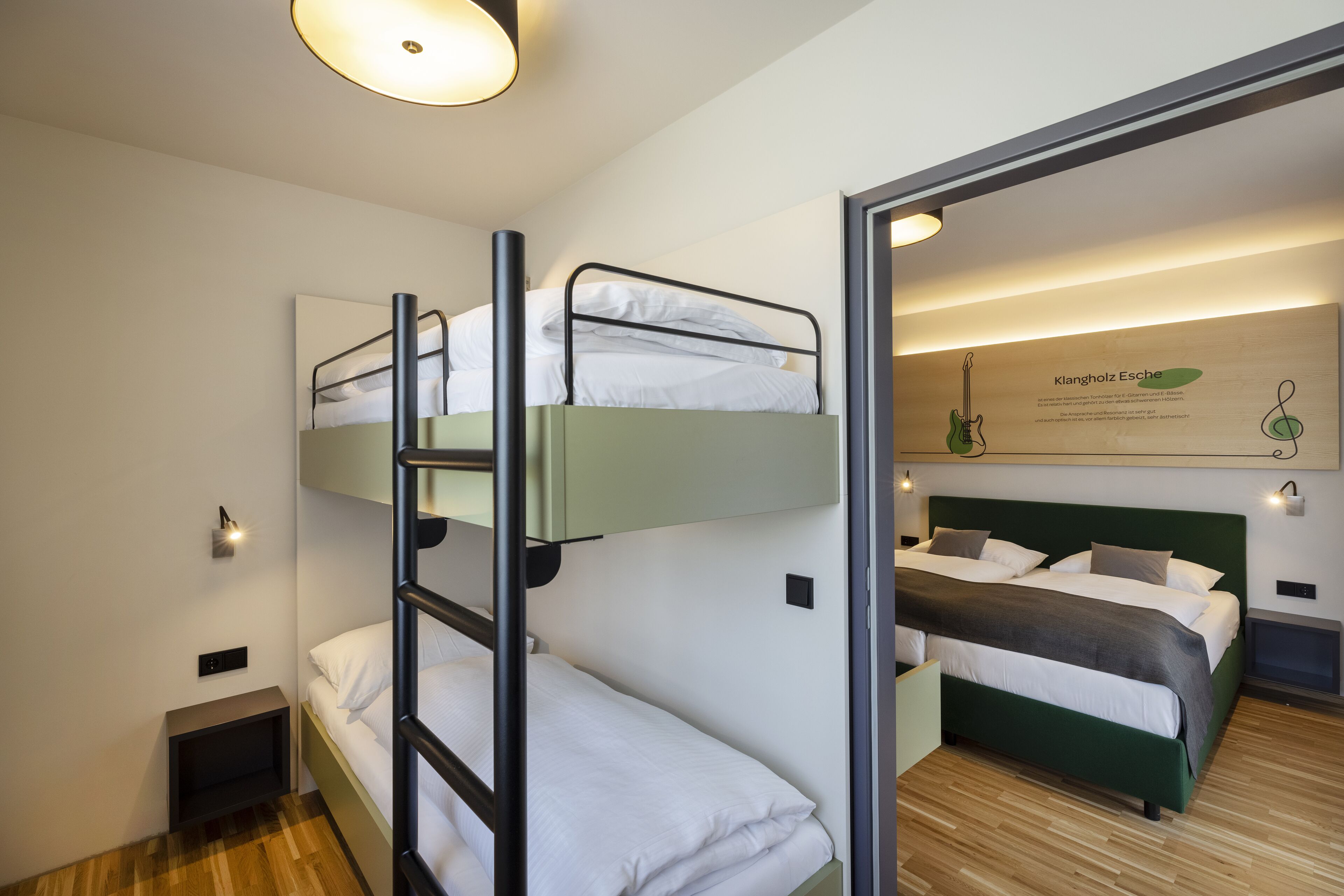 A bunk bed room with a mirror, a wall-mounted light, and a framed picture.