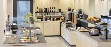 A modern kitchen with a buffet setup, including a variety of food items and a coffee station.