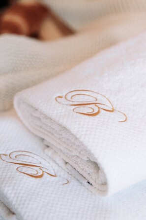 A stack of white towels with a gold embroidered monogram. - Apartments Babic (Rijeka)