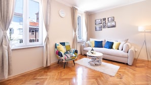 Un salon avec un canapé, un fauteuil coloré, une table basse et une lampe.