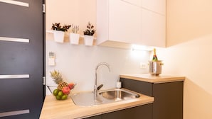 Une cuisine moderne avec un évier en acier inoxydable, un plan de travail en bois et une plante en pot accrochée au mur.