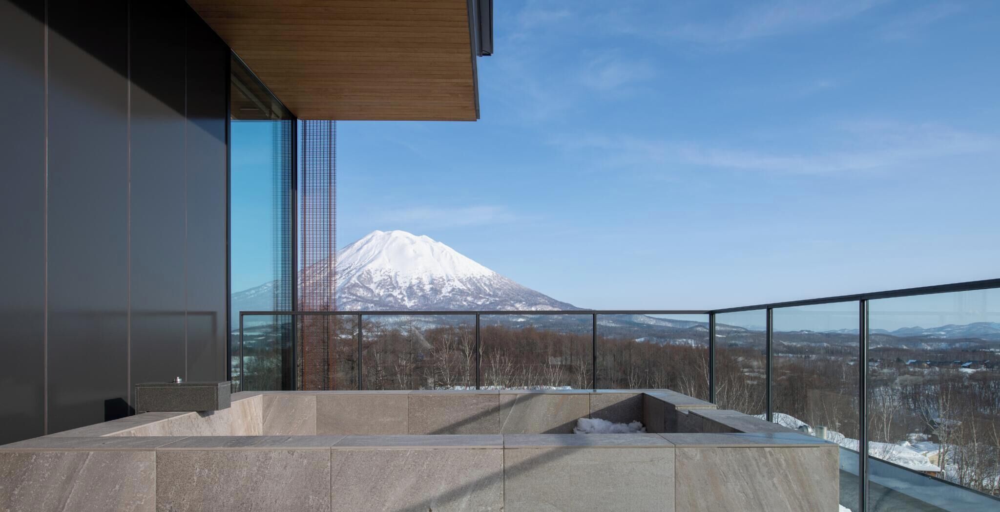 Un edificio moderno con un'ampia vetrata e vista su una montagna innevata.