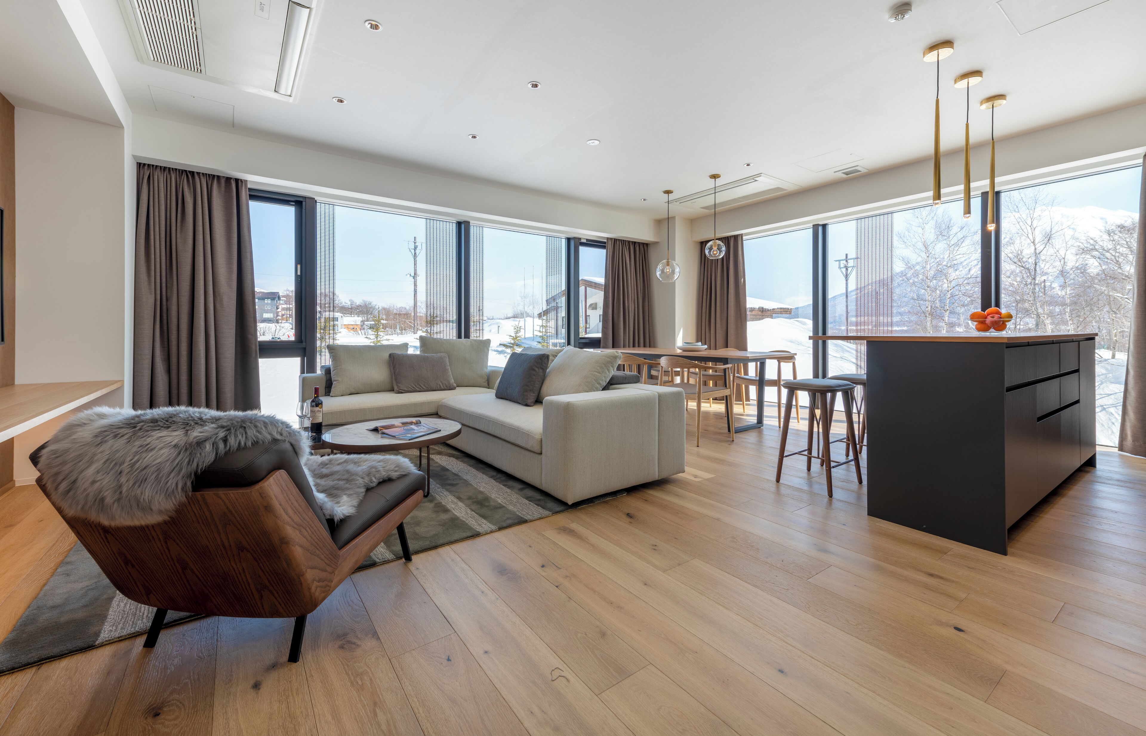 A modern living room with a sofa, armchair, and dining area.