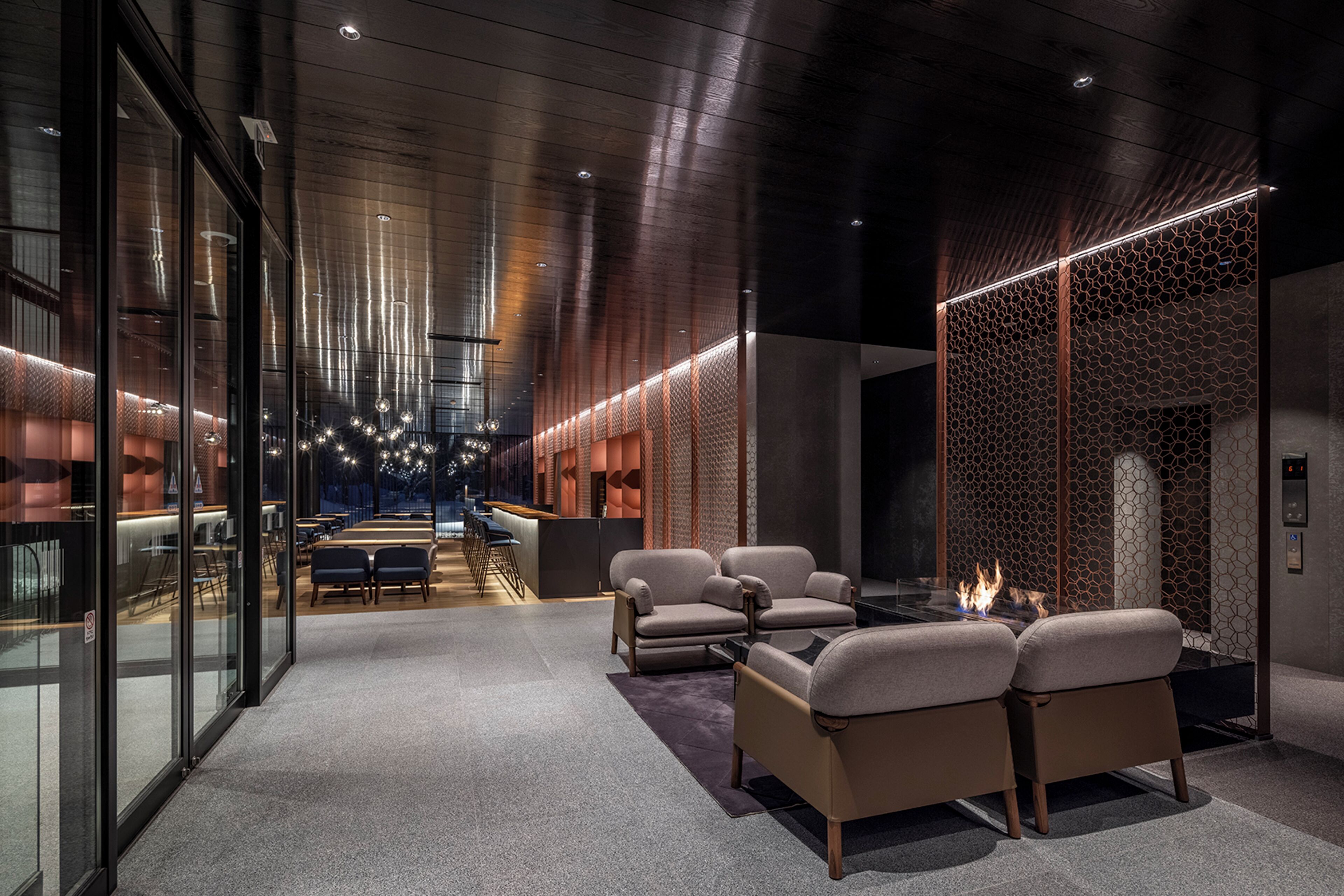 A modern lobby with a reception desk, seating area, and a decorative wall with a geometric pattern.