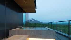 Un interior moderno con un banco de piedra y una barandilla de vidrio con vistas a la montaña.