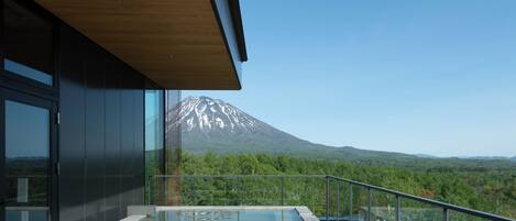 A modern building with a glass balcony overlooking a mountain.