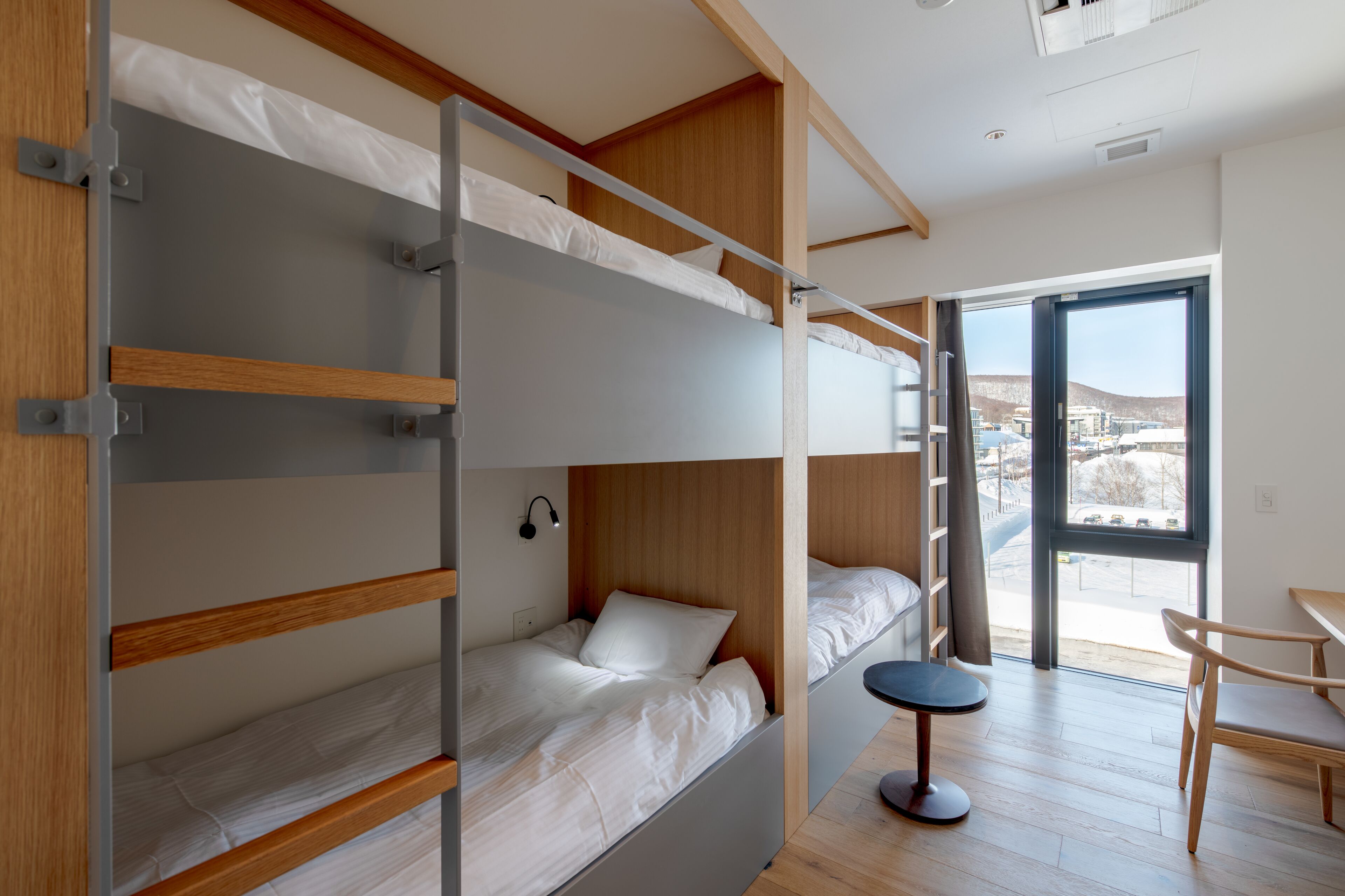 Ein modernes Zimmer mit Etagenbetten, einem kleinen Tisch und einem Stuhl.