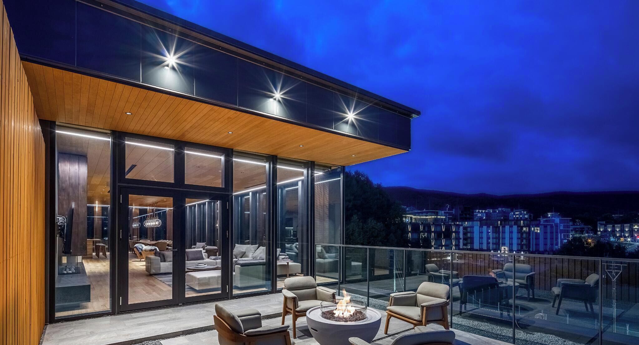 A modern building with a glass facade, outdoor seating area, and a fire pit.