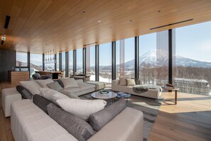 A spacious living room with a large sectional sofa, a coffee table, and a view of a snow-capped mountain. - Intuition (Kutchan)
