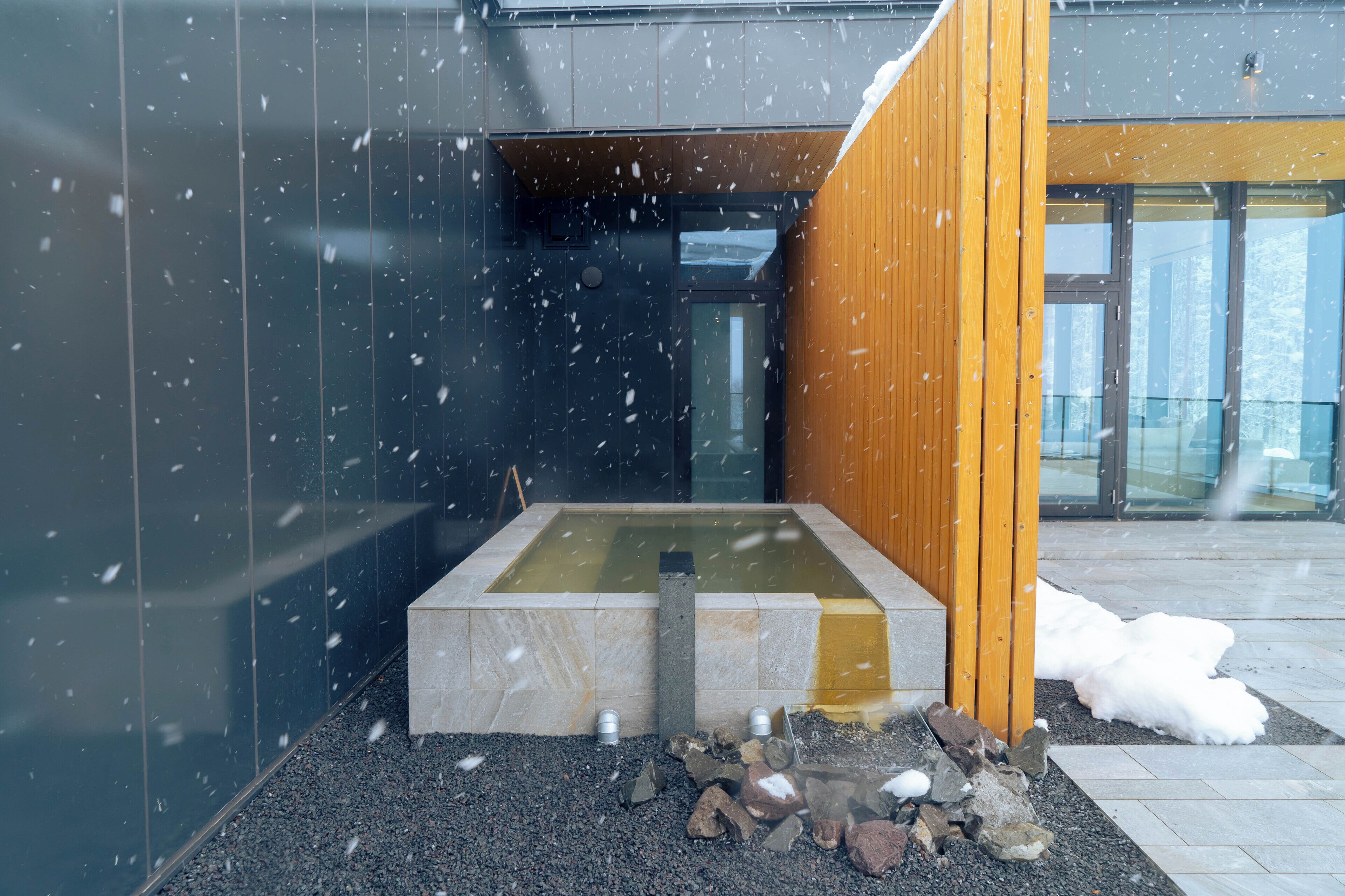 A modern building with a water feature and a wooden panel.