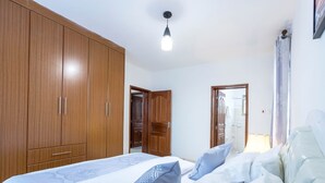 Ein Schlafzimmer mit großem Kleiderschrank, einem Bett mit vielen Kissen und einer Deckenleuchte.