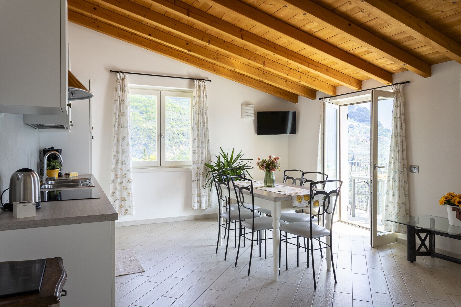 Eine moderne Küche mit eingebautem Herd, ein Essbereich mit Tisch und Stühlen sowie ein Balkon mit Blick.