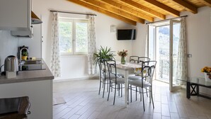 A modern kitchen with a built-in stove, a dining area with a table and chairs, and a balcony with a view.