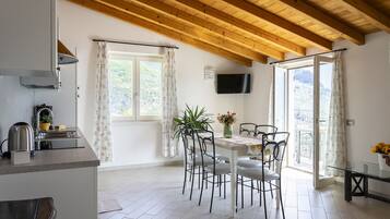 Eine moderne Küche mit eingebautem Herd, ein Essbereich mit Tisch und Stühlen sowie ein Balkon mit Blick.