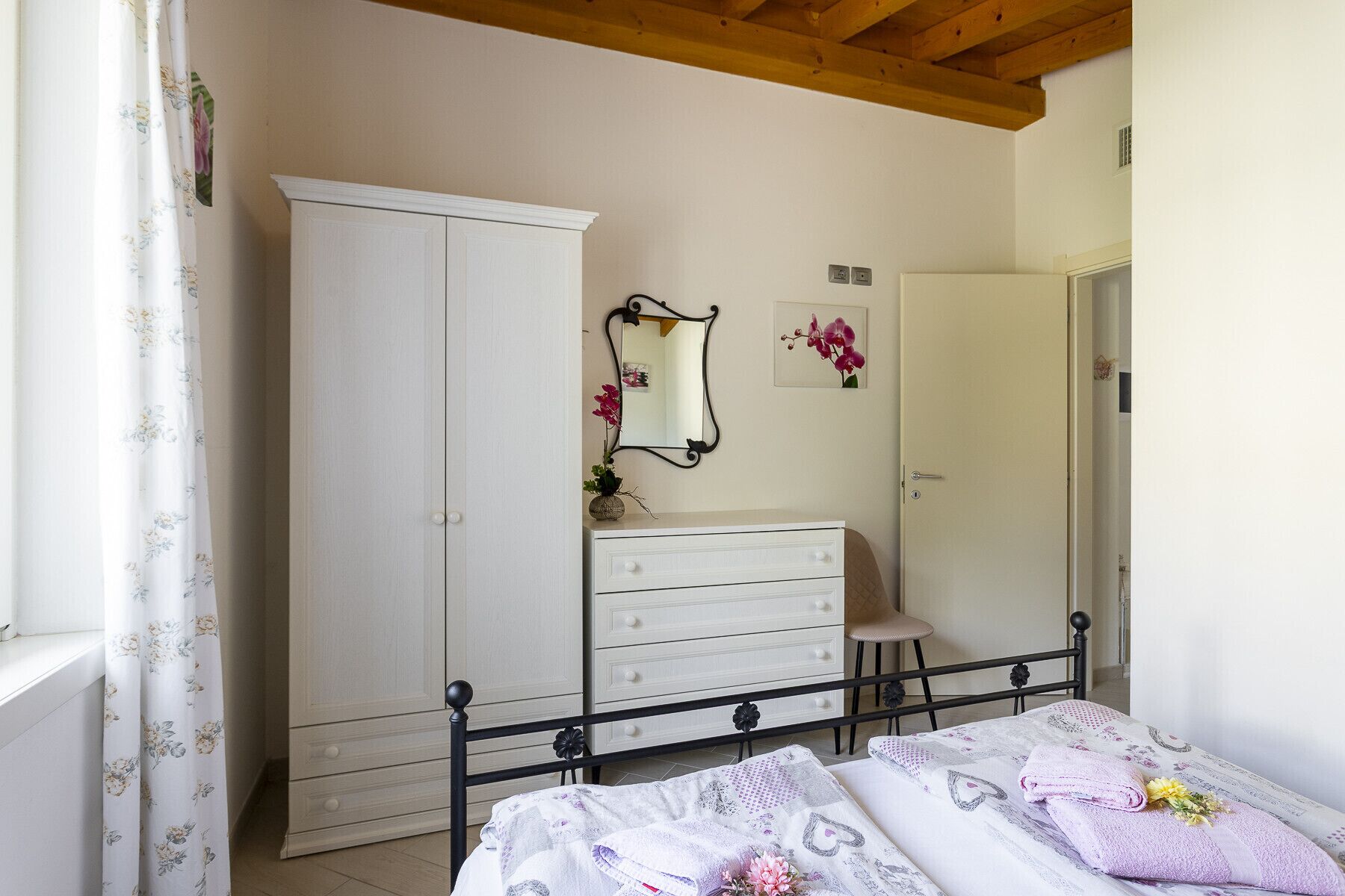 Ein Schlafzimmer mit Bett, Kommode, Spiegel und Kleiderschrank.