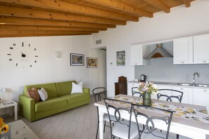 Eine moderne Küche mit weißen Schränken, einer Holzbalkendecke und einem Essbereich mit Tisch und Stühlen.