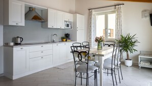 A modern kitchen with white cabinets, a wooden ceiling, and a dining area with a table and chairs.