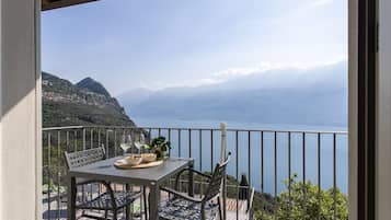 Ein Balkon mit Tisch, Stühlen und Blick auf einen See und Berge.