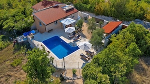 An aerial view of a house with a swimming pool, surrounded by trees and a red-roofed structure. - Villa Melita with heated pool in Biokovo Nature Park near Makarska (Zagvozd)