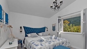A bedroom with a large bed, a bedside table, a chair, a window with a view of greenery, and a chandelier. - Villa Melita with heated pool in Biokovo Nature Park near Makarska (Zagvozd)