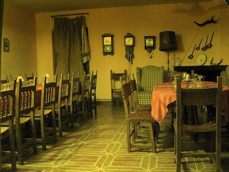 A dining area with wooden chairs and tables, a patterned floor, and wall-mounted clocks.