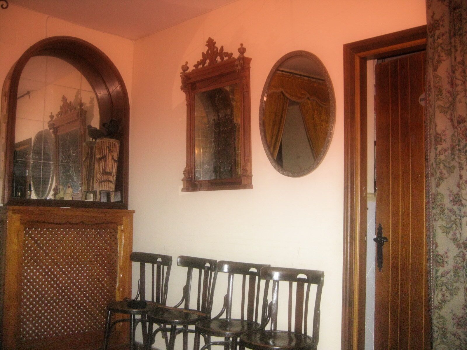 A room with a wooden bench, a mirror, and a door.