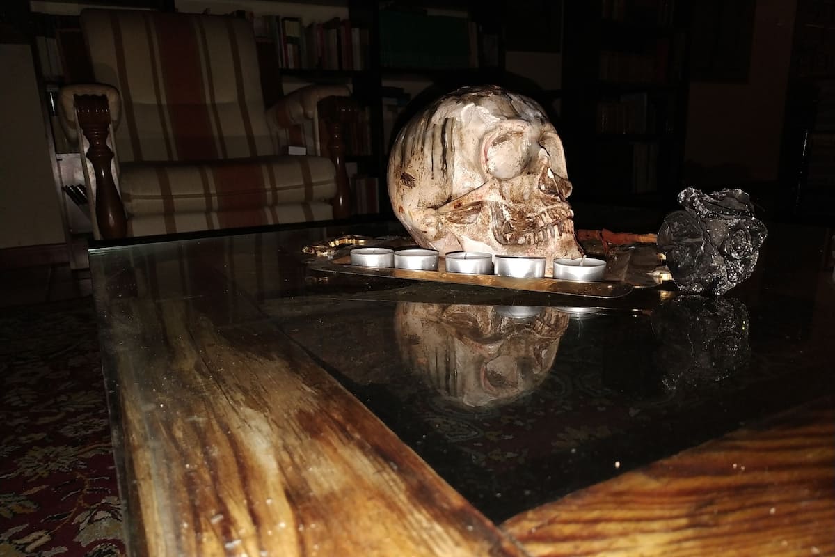 A wooden table with a skull centerpiece and candles.