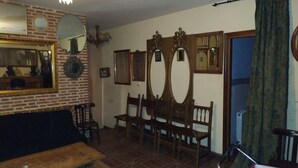 A living room with a brick wall, a wooden bench, a sofa, and a dining table. - La Casa del Miedo (San Martin de Montalban)