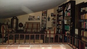 A cozy living room with a fireplace, a large bookshelf, and a comfortable seating area. - La Casa del Miedo (San Martin de Montalban)