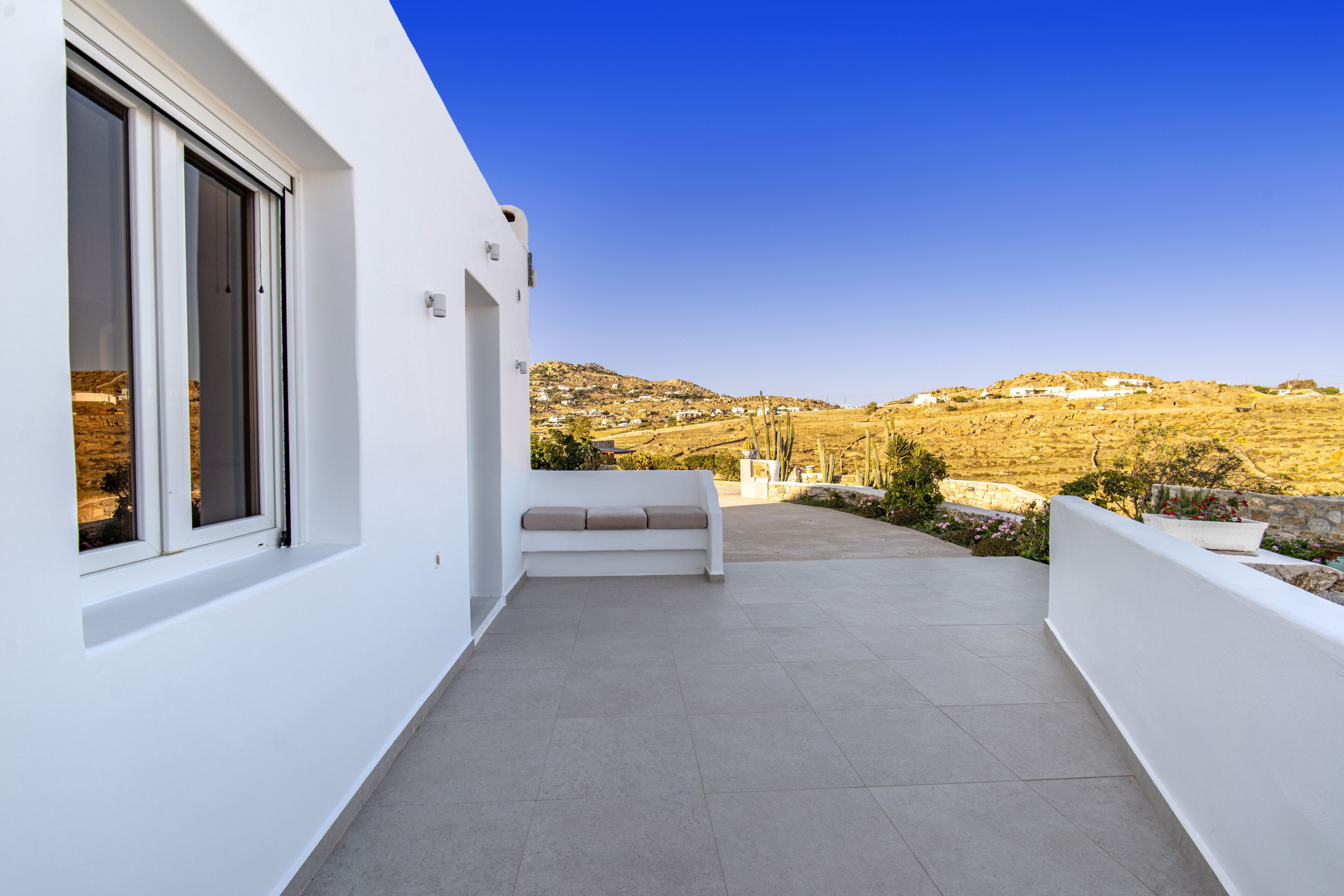 A modern white building with a balcony overlooking a hilly landscape.