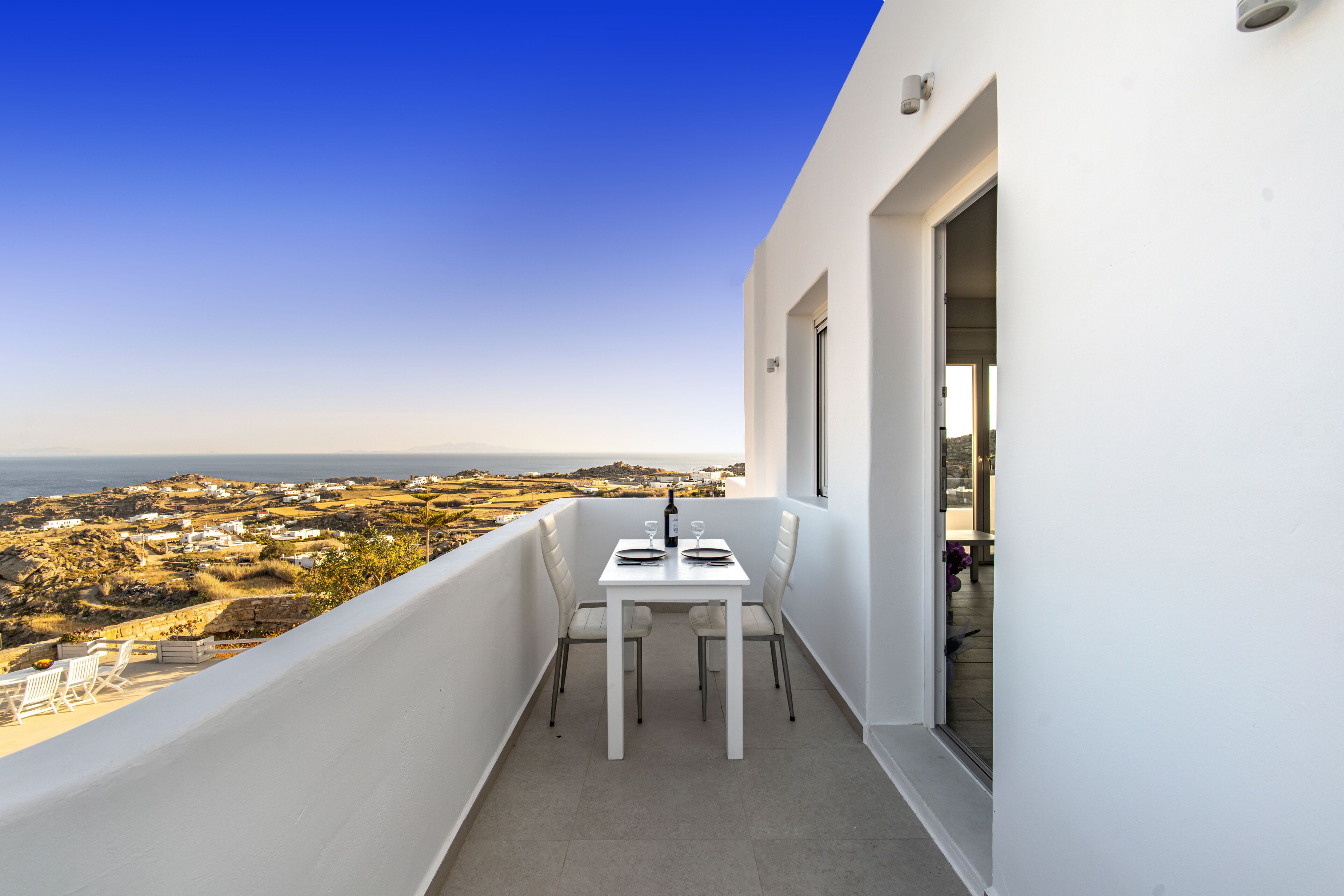 Ein Balkon mit Tisch und Stühlen mit Blick auf eine Küstenlandschaft.