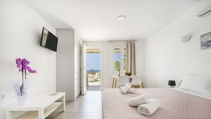 Habitación de hotel moderna con cama, escritorio, silla, televisor y vistas al exterior.