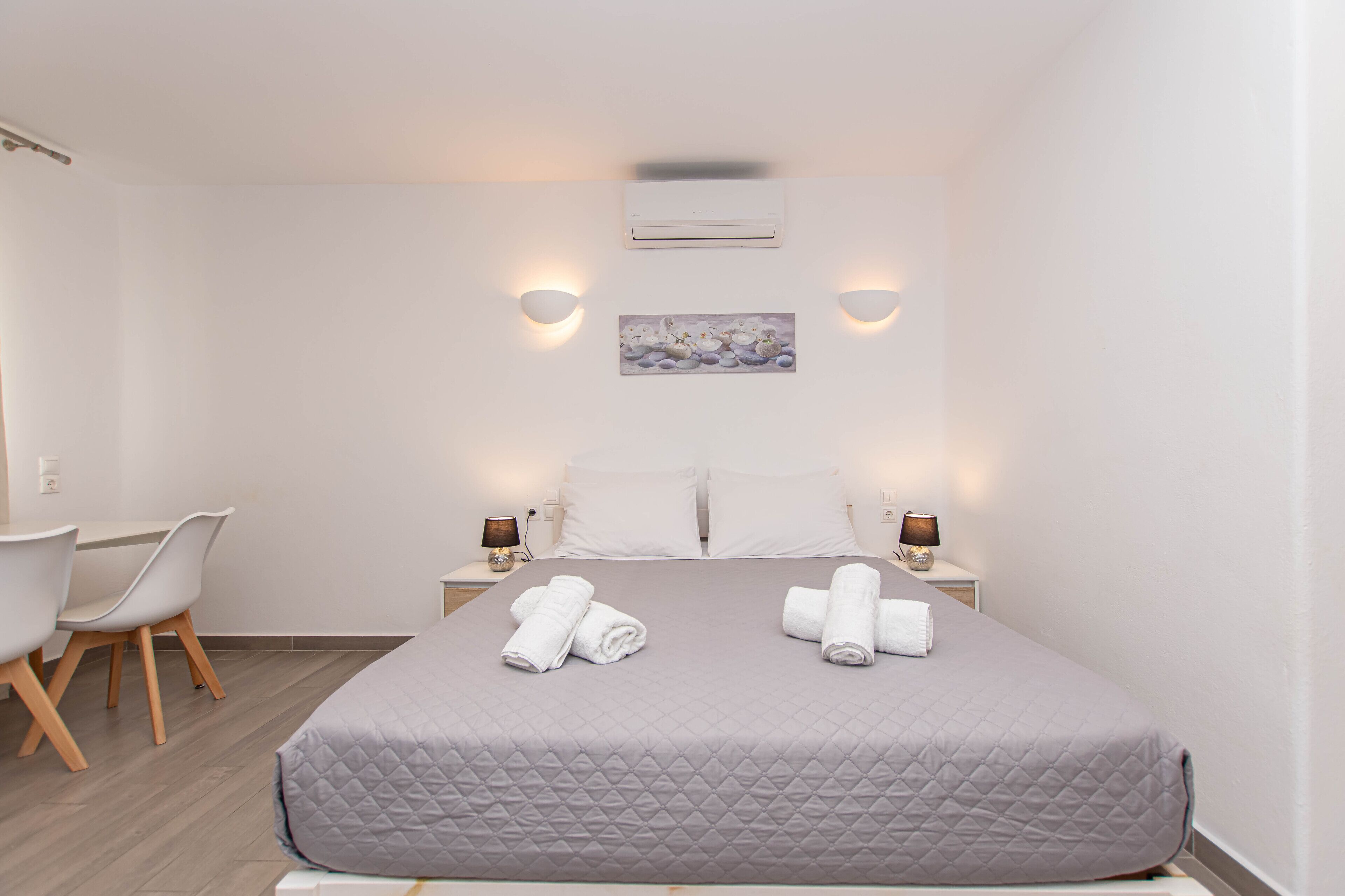 Una habitación de hotel moderna con una cama, dos mesitas de noche, un escritorio y sillas.