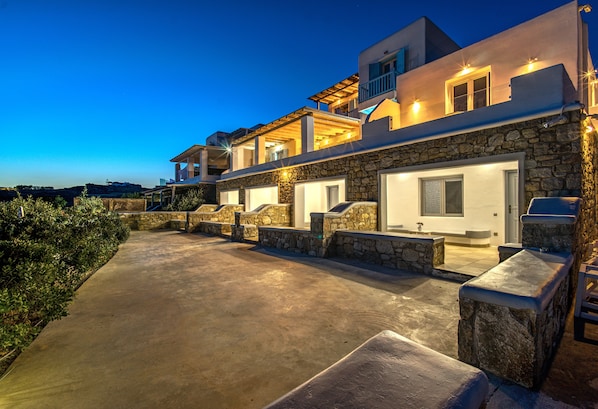 A modern house with a stone facade, multiple balconies, and a well-lit driveway.
