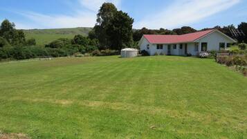 A single-story house with a red roof, surrounded by a well-maintained lawn and a few trees.