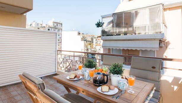 A balcony with a table set for breakfast, including bread, eggs, and fruit. - Nephiria's Boho House with Acropolis View (Athens)