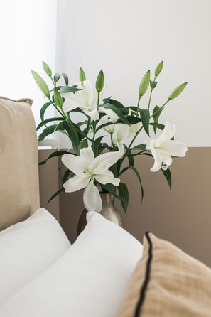 Un vase rempli de lys blancs, posé sur un canapé beige.