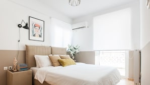 A bedroom with a bed, bedside table, lamp, and a framed picture on the wall. - Nephiria's Boho House with Acropolis View (Athens)