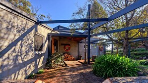Una propiedad residencial con un espacio exterior cubierto, un muro de piedra y una terraza de madera.