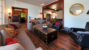 A cozy living room with a vintage suitcase coffee table, leather sofas, and a round mirror on the wall.