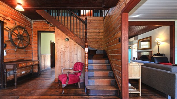 A wooden interior with a staircase, a red chair, and a sofa.