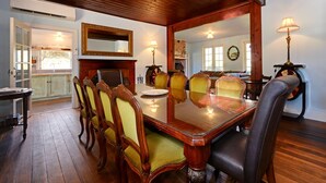 A dining room with a wooden table and chairs, a fireplace, and a mirror on the wall.